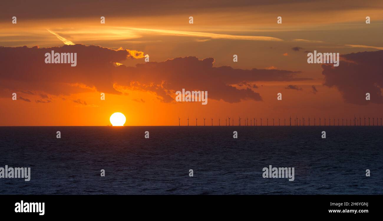 Off shore wind farm with setting sun on the horizon. Stock Photo