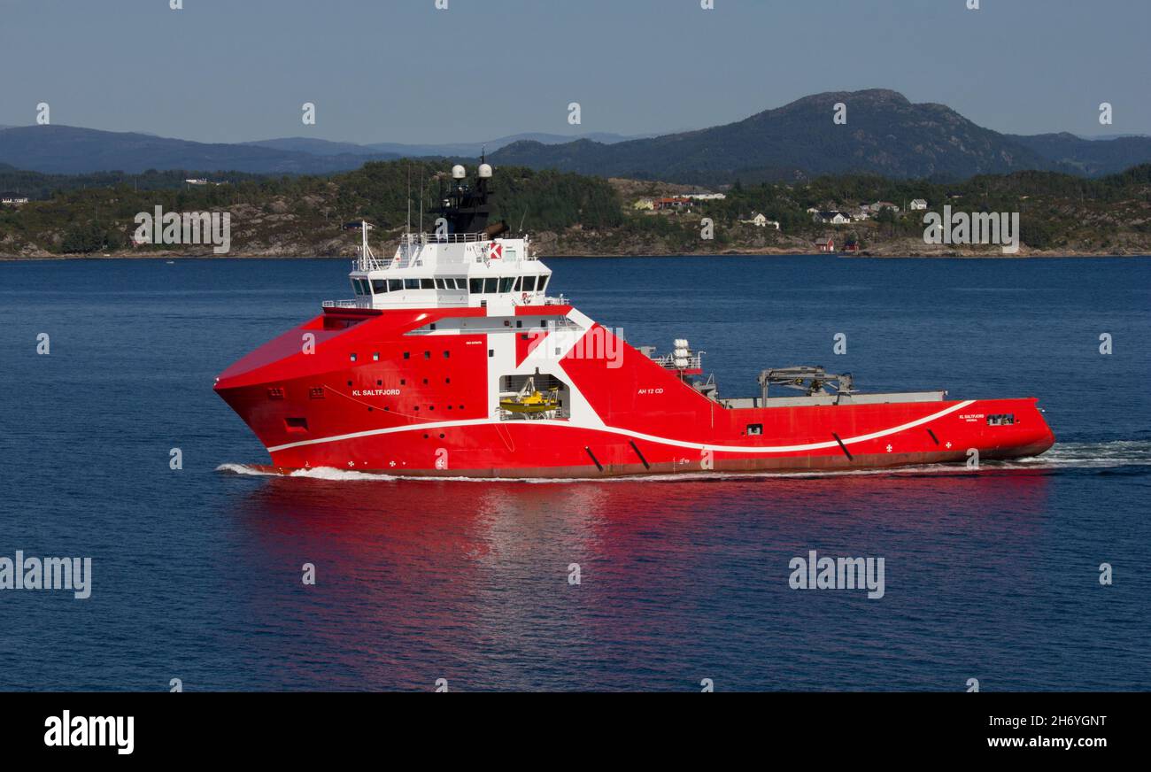 KL Saltfjord, anchor handling tug supply vessel for 'K' line.  Sailing from Bergen, Norway.  Norwegian coastline and mountains in background. Stock Photo