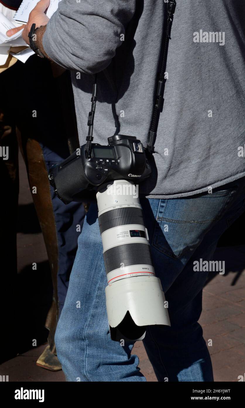 A newspaper photojournalist using a Canon camera with a telephoto zoom lens on the job during an event in Santa Fe, New Mexico. Stock Photo