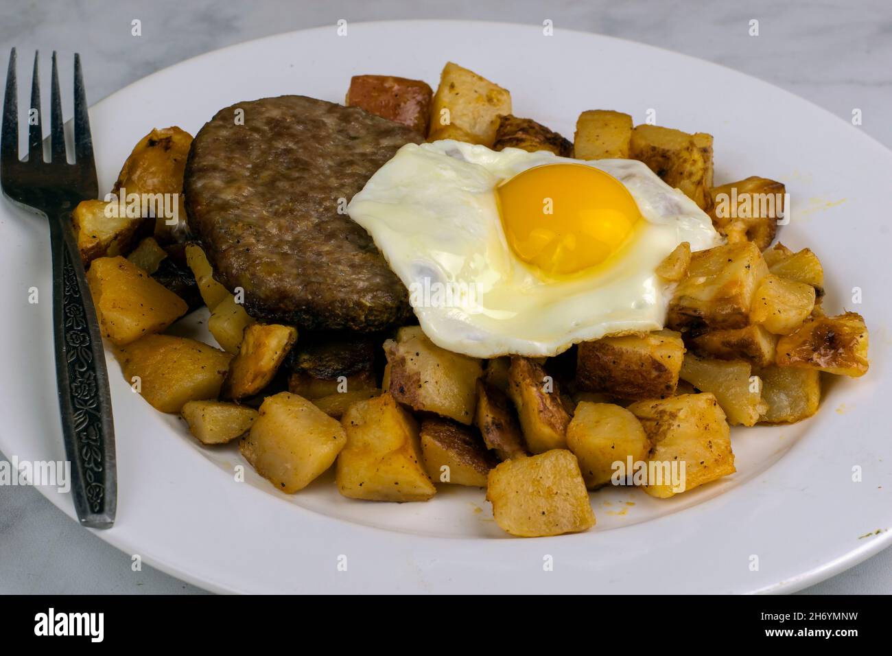 breakfast plate with fried egg, sausage,patty on home fries Stock Photo