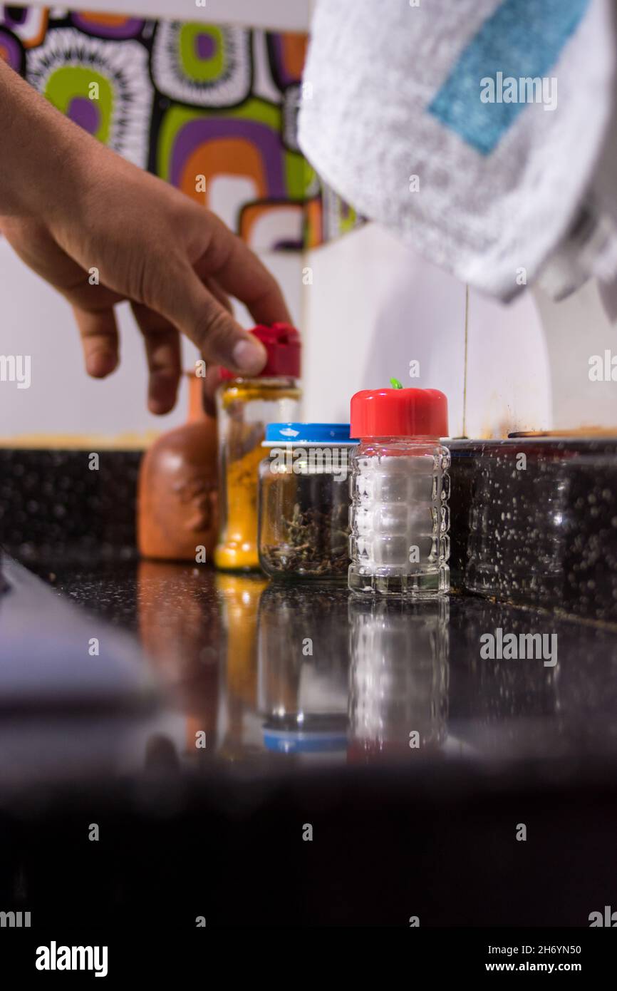 Hand putting on a cooking spices pot on a kitchen meson in a kitchen at home Stock Photo