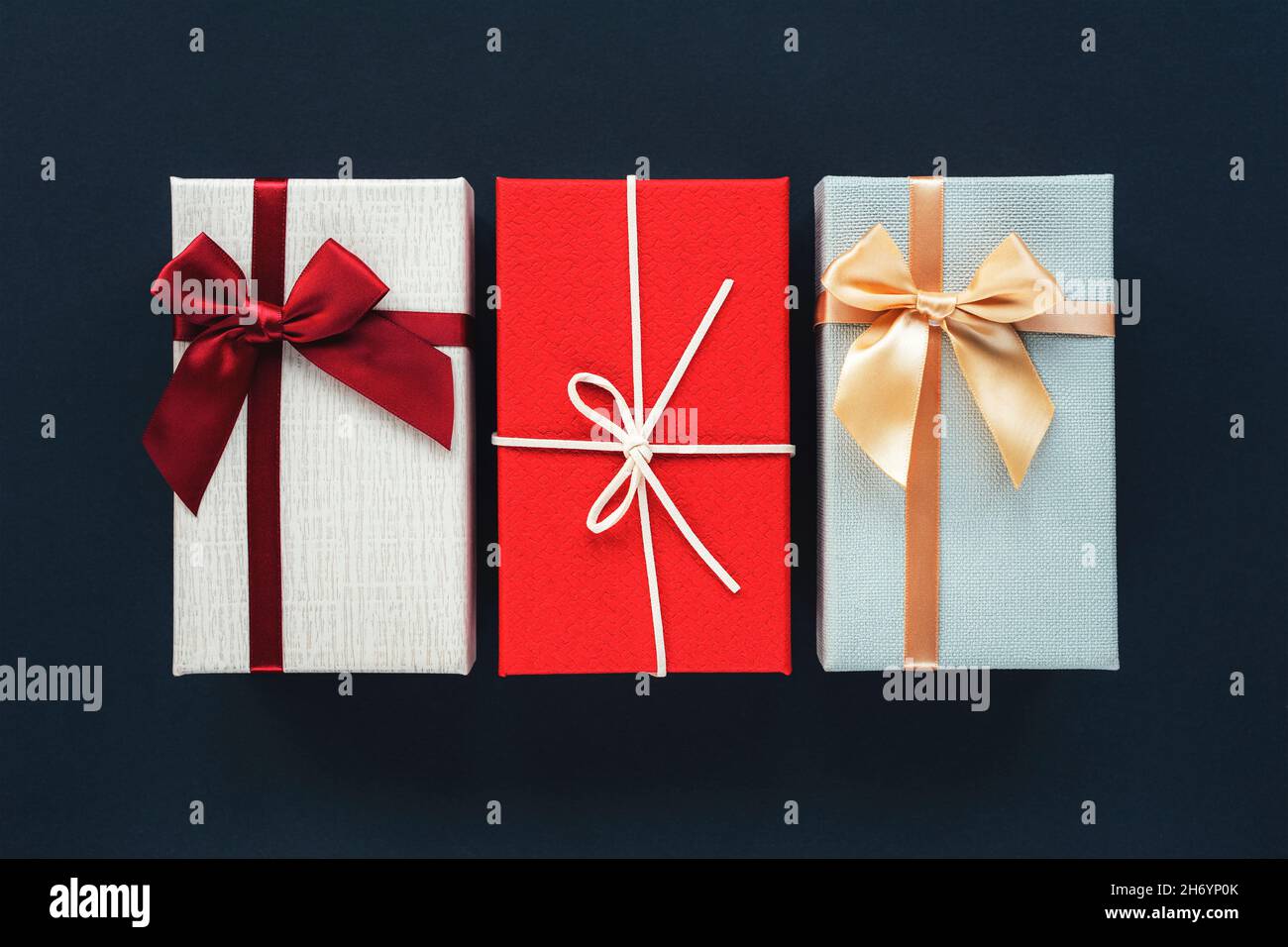 Three gift boxes on black background. Christmas concept. Top view, flat lay, copy space. Stock Photo