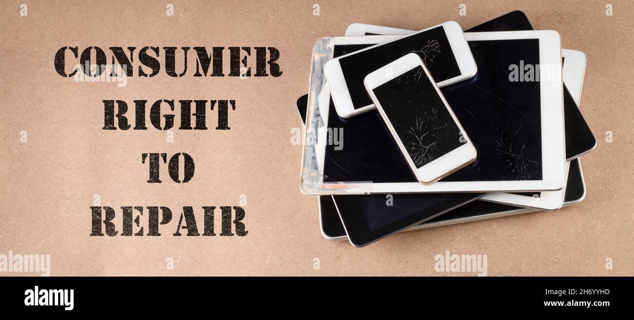 consumer right to repair text next to broken tablets and smart phones on board consumer right to repair goods Stock Photo