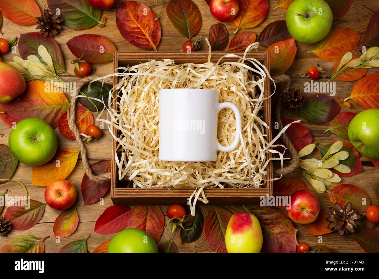 White coffee mug rustic mockup with fall leaves, apples and pine cones. Empty mug mock up for design promotion, styled template Stock Photo