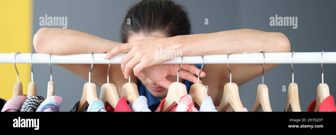 Pensive woman stands near hanger with clothes Stock Photo Alamy