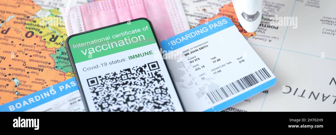 On smartphone screen certificate of immunity against Covid 19 and plane ticket. Stock Photo