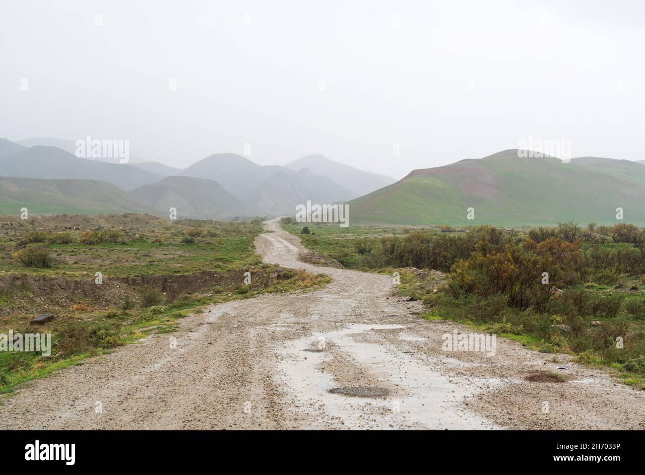 Wet dirt road leading to the mountains Stock Photo Alamy