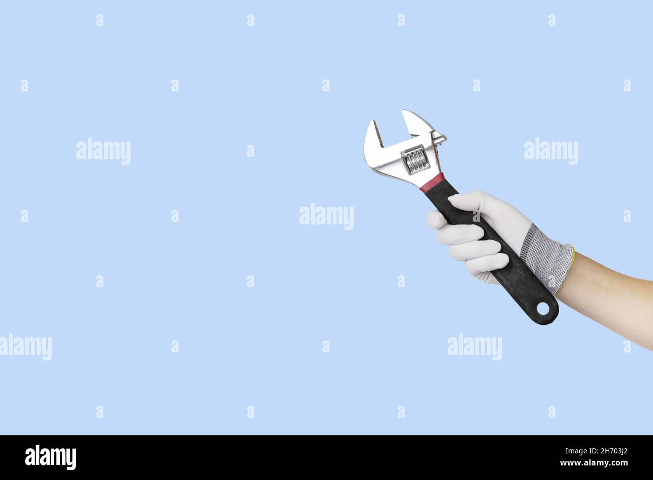 Gloved hands holding spanner construction tools. Work tools on blue background Stock Photo