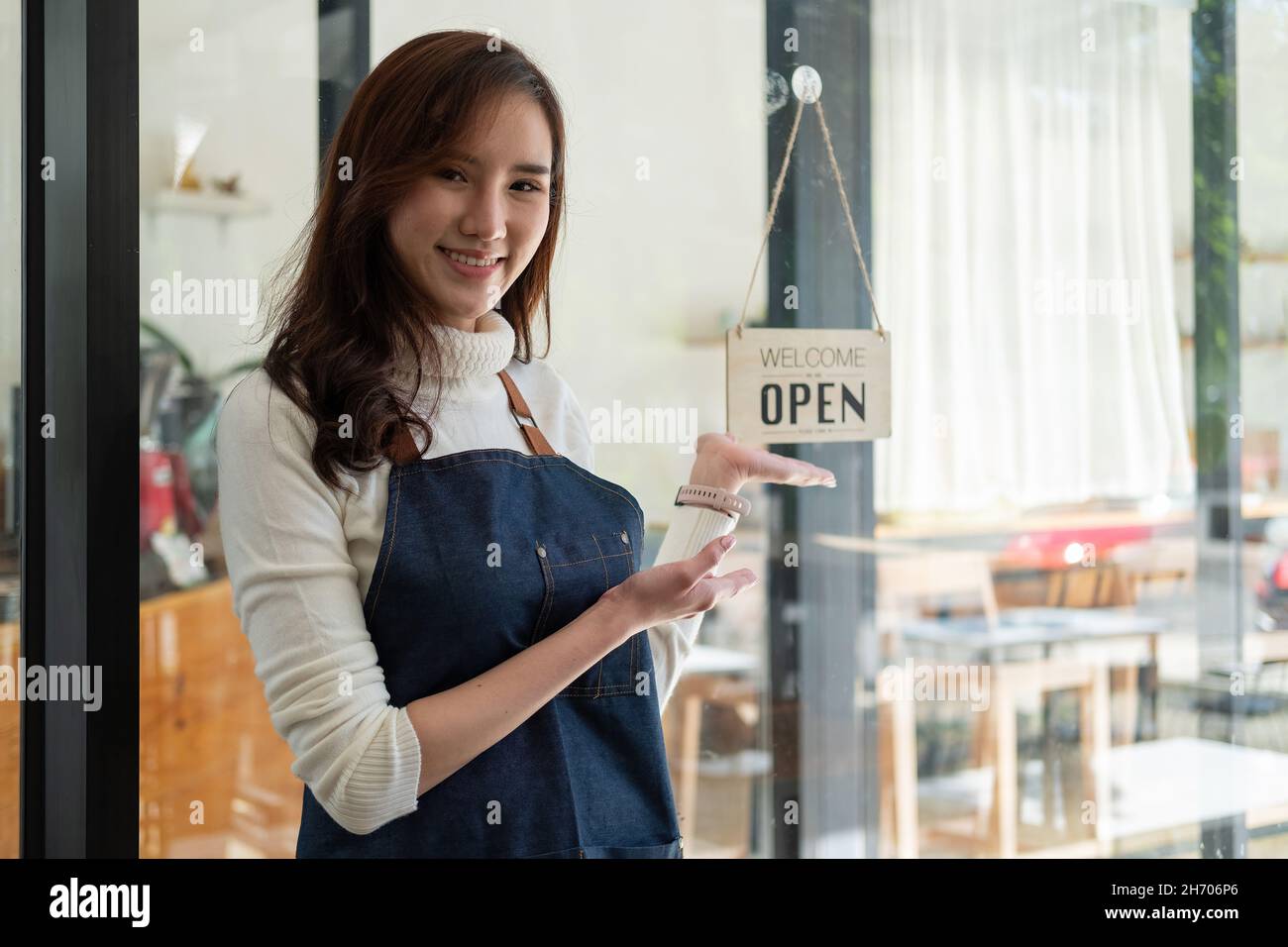 Portrait Of A Smiling Asian Entrepreneur Standing Behind Her Cafe
