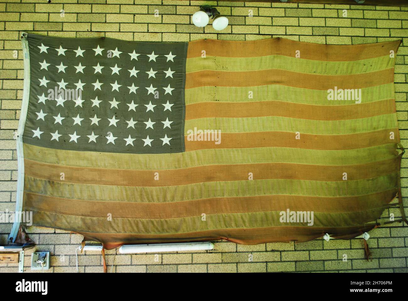 Old Tattered American Flag Hangs on a Small Barn Stock Photo