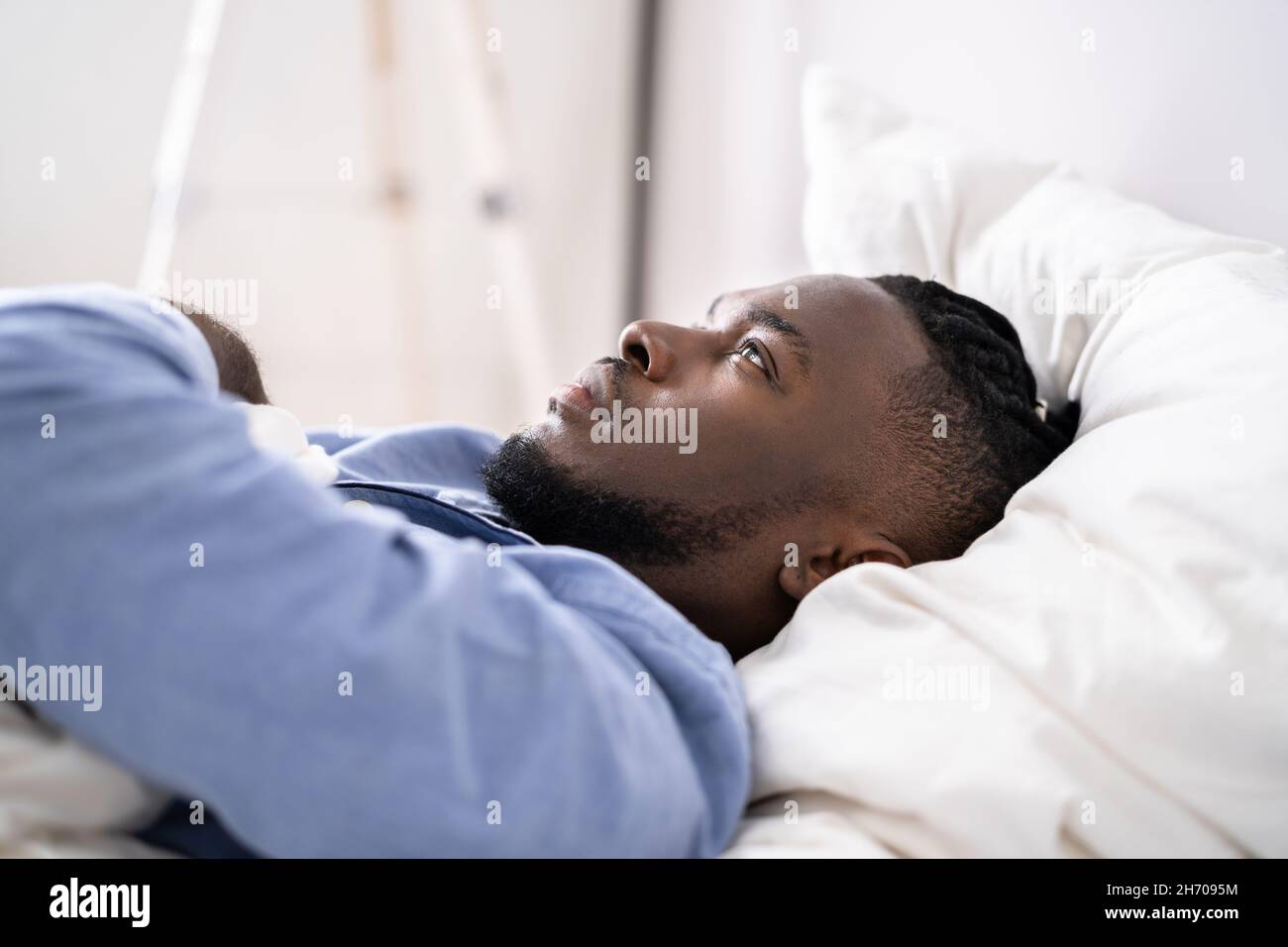Young Man Suffering From Insomnia Lying In His Bed Stock Photo