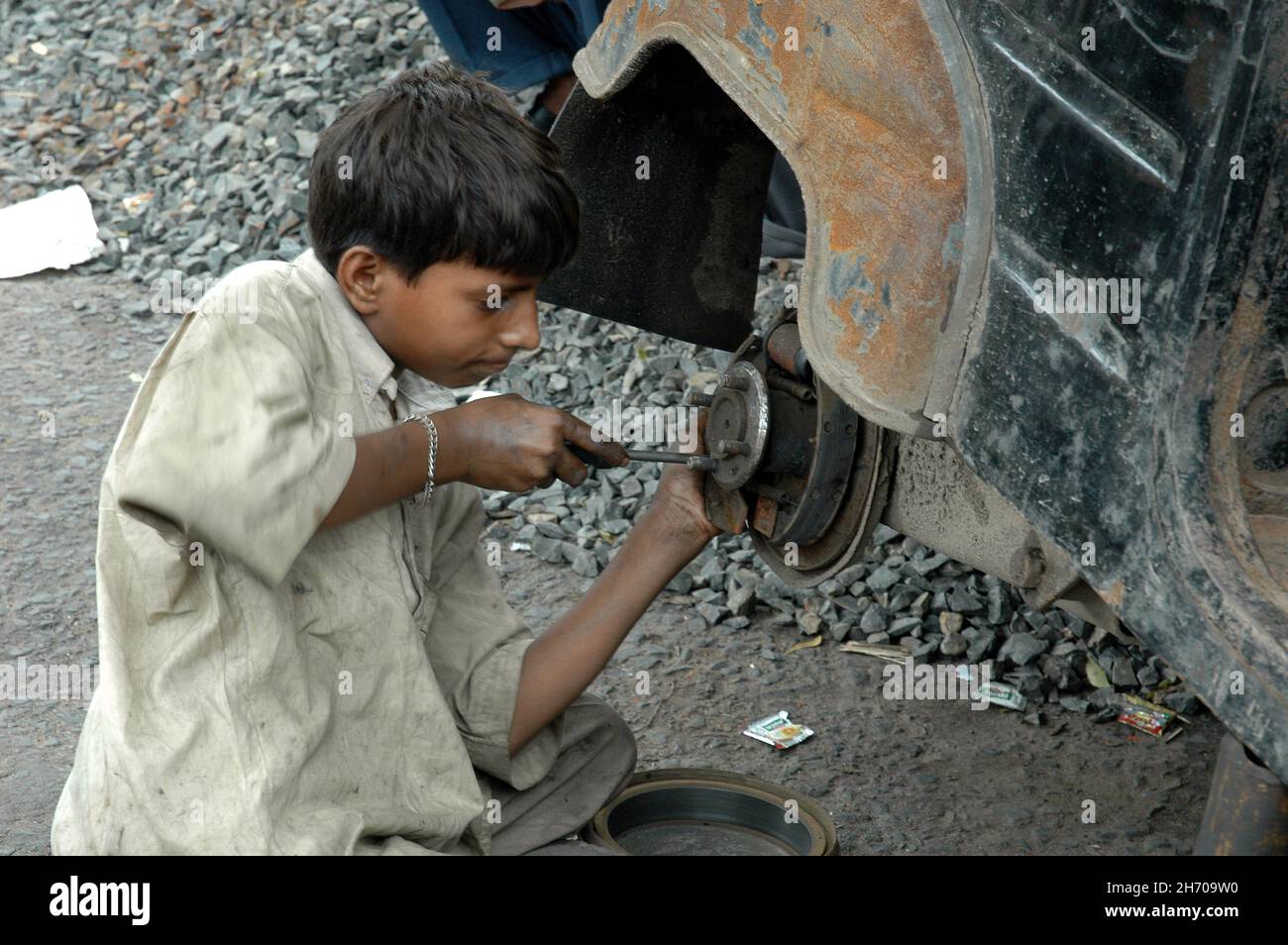 small boy working on a three wheeler trying to fix the breaks. India Stock Photo Alamy
