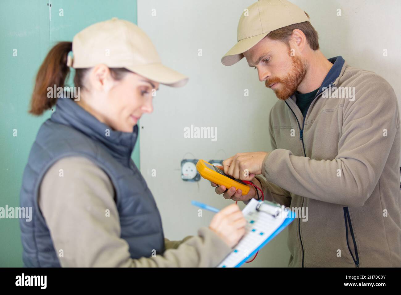 male and female electricians at work at new construction site Stock