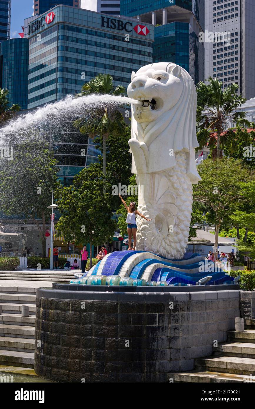 Singapore, 23 Feb 2016: Tourist having fun posing with iconic landmark Merlion. Stock Photo