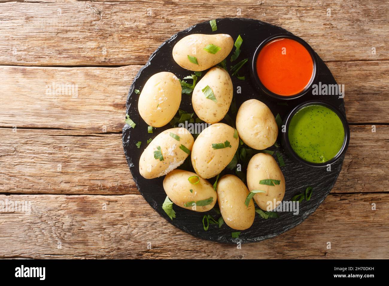 Canarian food wrinkly potatoes are boiled unpeeled potatoes served with two local sauces close-up on a slate plate on the table. horizontal top view f Stock Photo