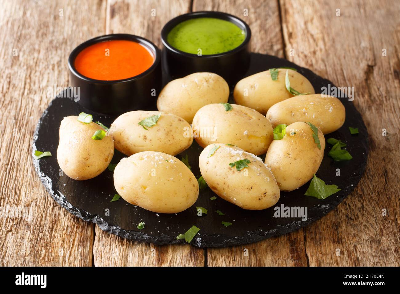 Canarian Wrinkled Potatoes Papas Arrugadas with Mojo close up in the plate on the table. Horizontal Stock Photo