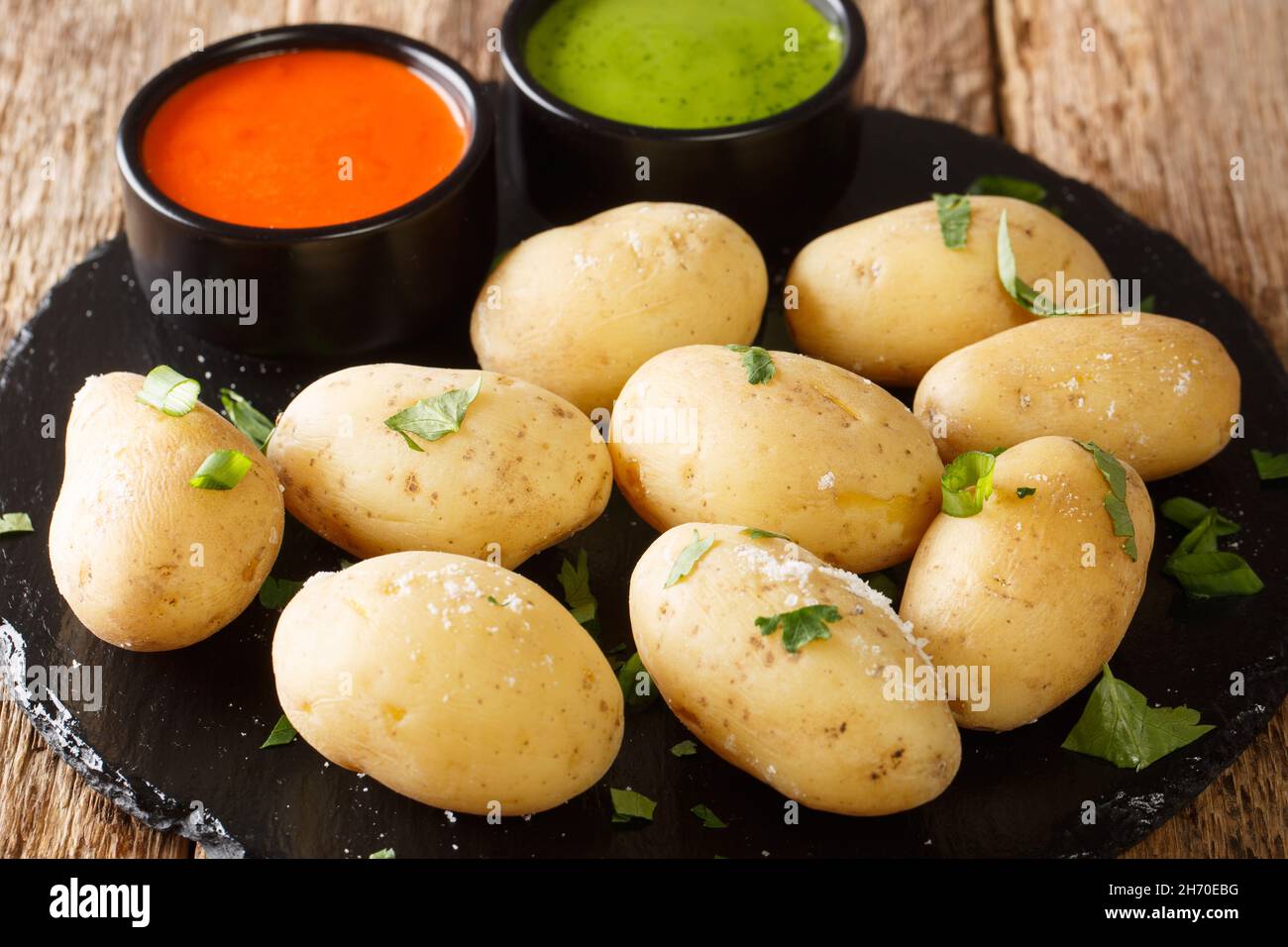 Canarian food wrinkly potatoes are boiled unpeeled potatoes served with two local sauces close-up on a slate plate on the table. horizontal Stock Photo