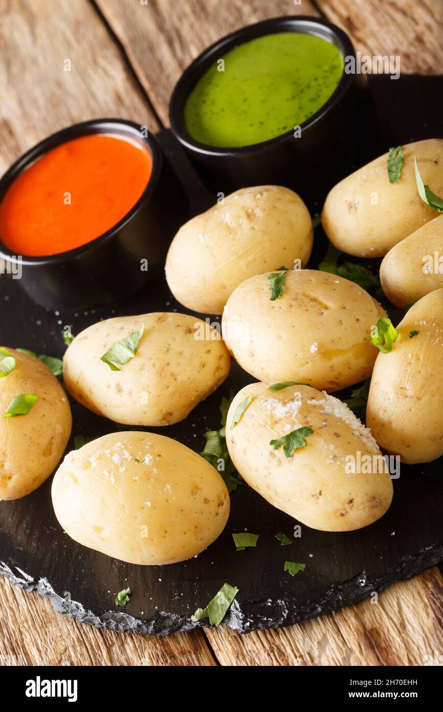 Papas arrugadas wrinkly potatoes is the signature dish of the Canary Islands close up in the plate on the table. Vertical Stock Photo