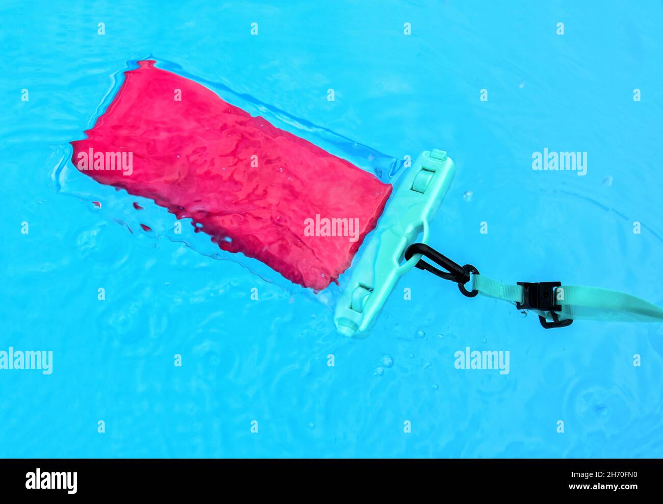 From above cellphone in transparent waterproof case floating in transparent water of pool Stock Photo