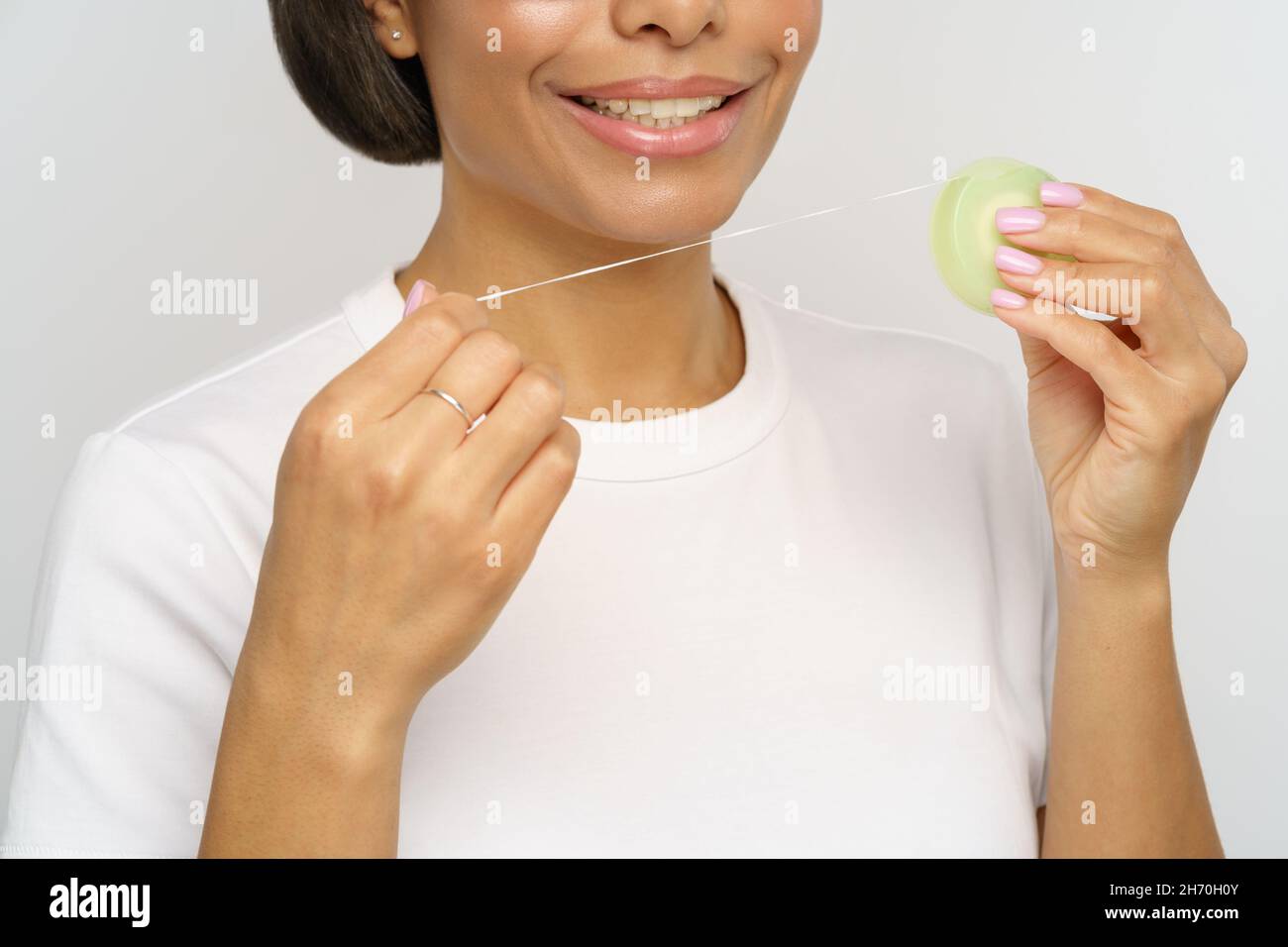 Female using tooth floss smile with healthy white teeth. Young woman flossing, doing morning routine Stock Photo