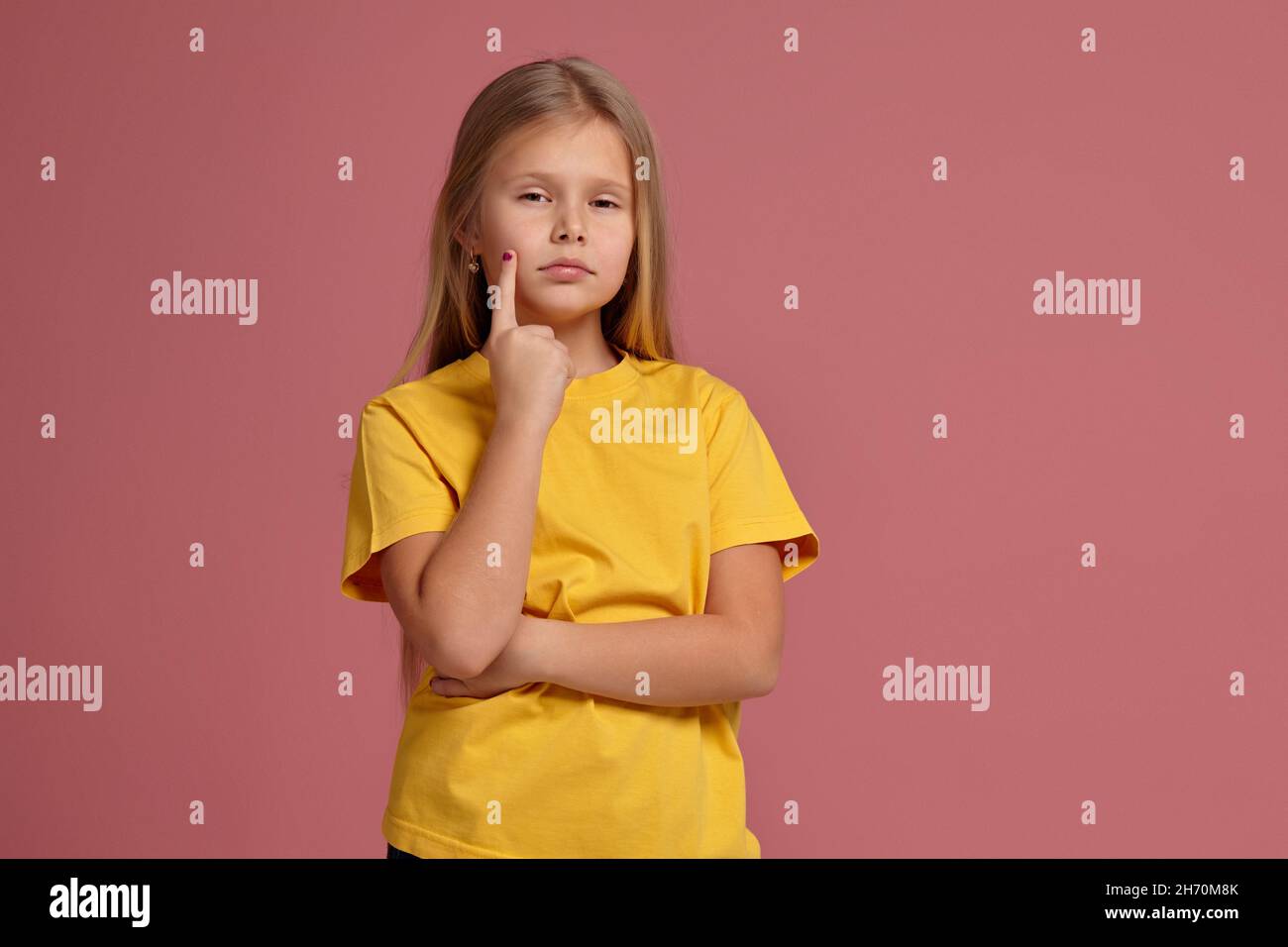 little girl in a yellow t-shirt. thoughtfully shows finger Stock Photo