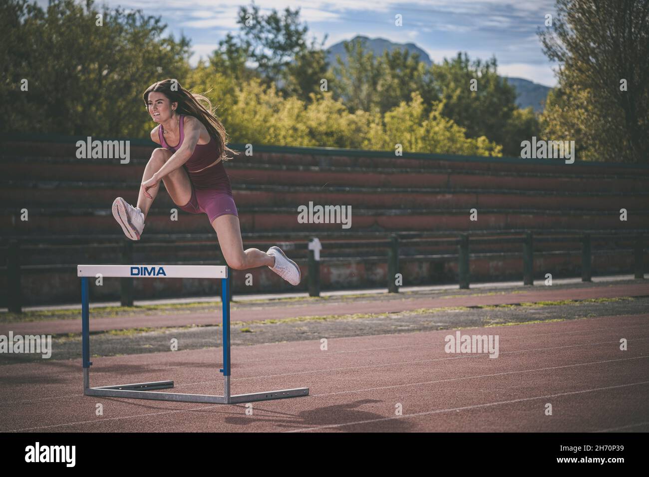 Athlete model girl jumping hurdles on the running track Stock Photo Alamy
