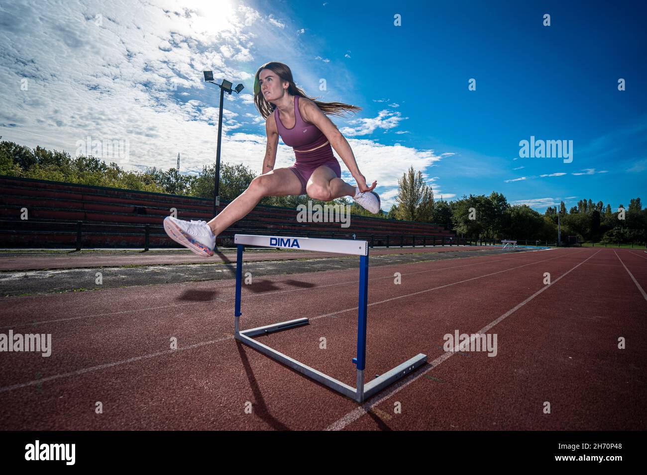 Athlete model girl jumping hurdles on the running track Stock Photo Alamy