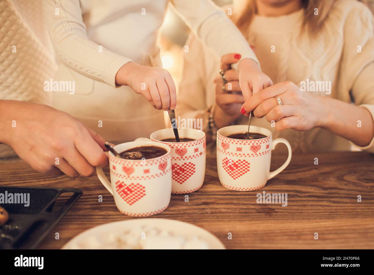 A cup with heart-shaped marshmallows, close-up on a blue wooden background.  Stock Photo by puhimec