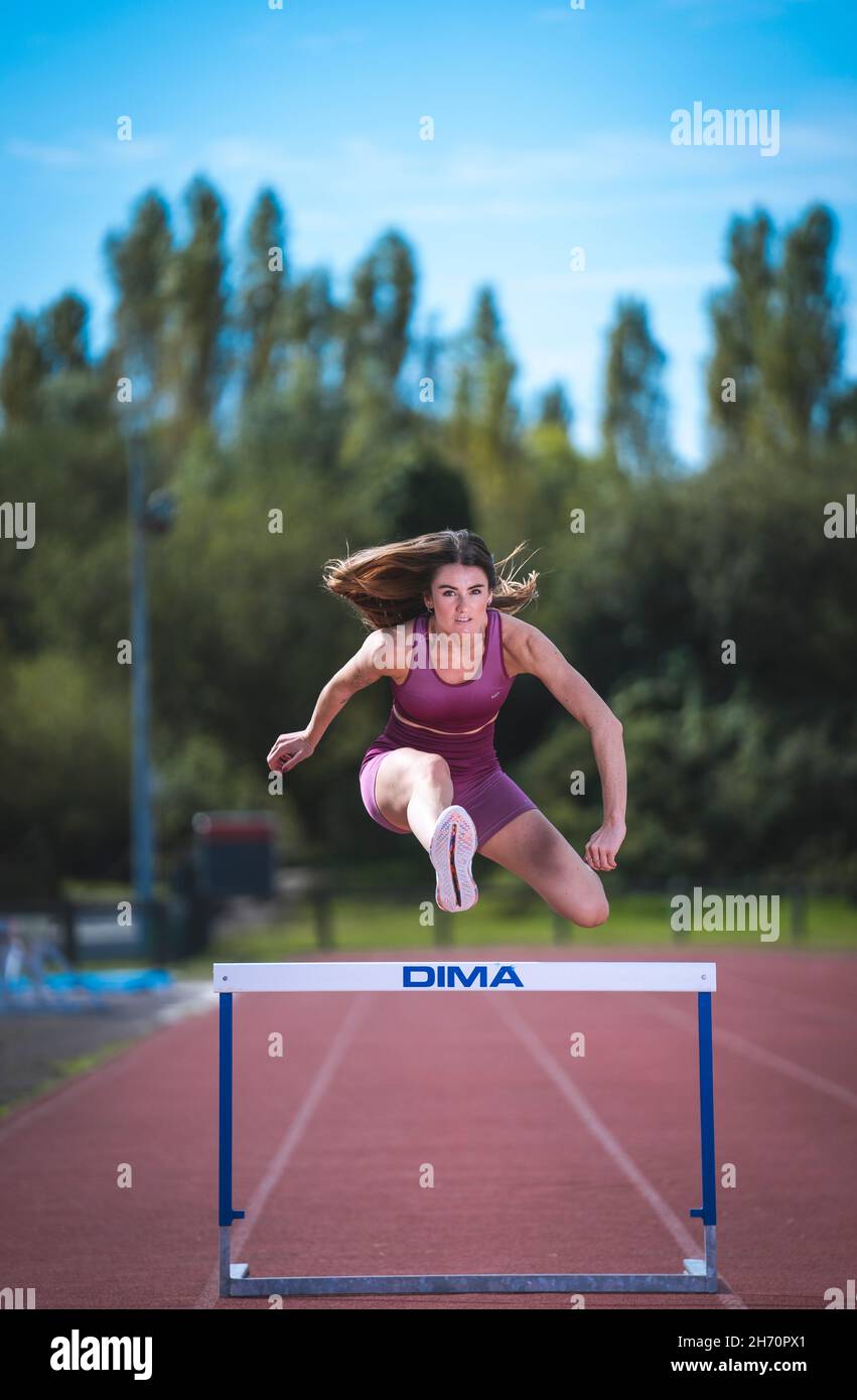 Athlete model girl jumping hurdles on the running track Stock Photo Alamy