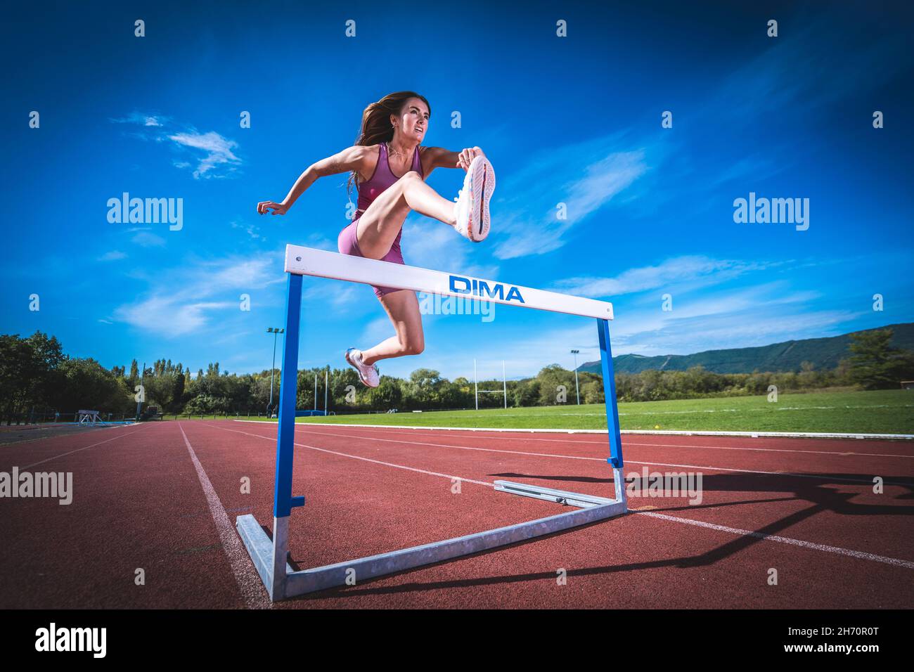 Athlete model girl jumping hurdles on the running track Stock Photo Alamy