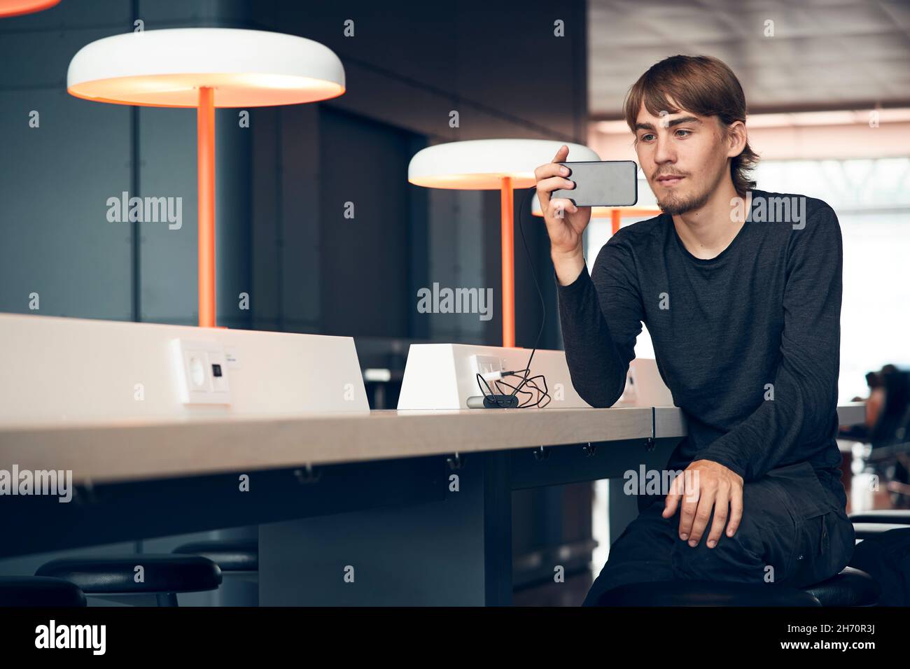 Man in library taking photo with cell phone Stock Photo