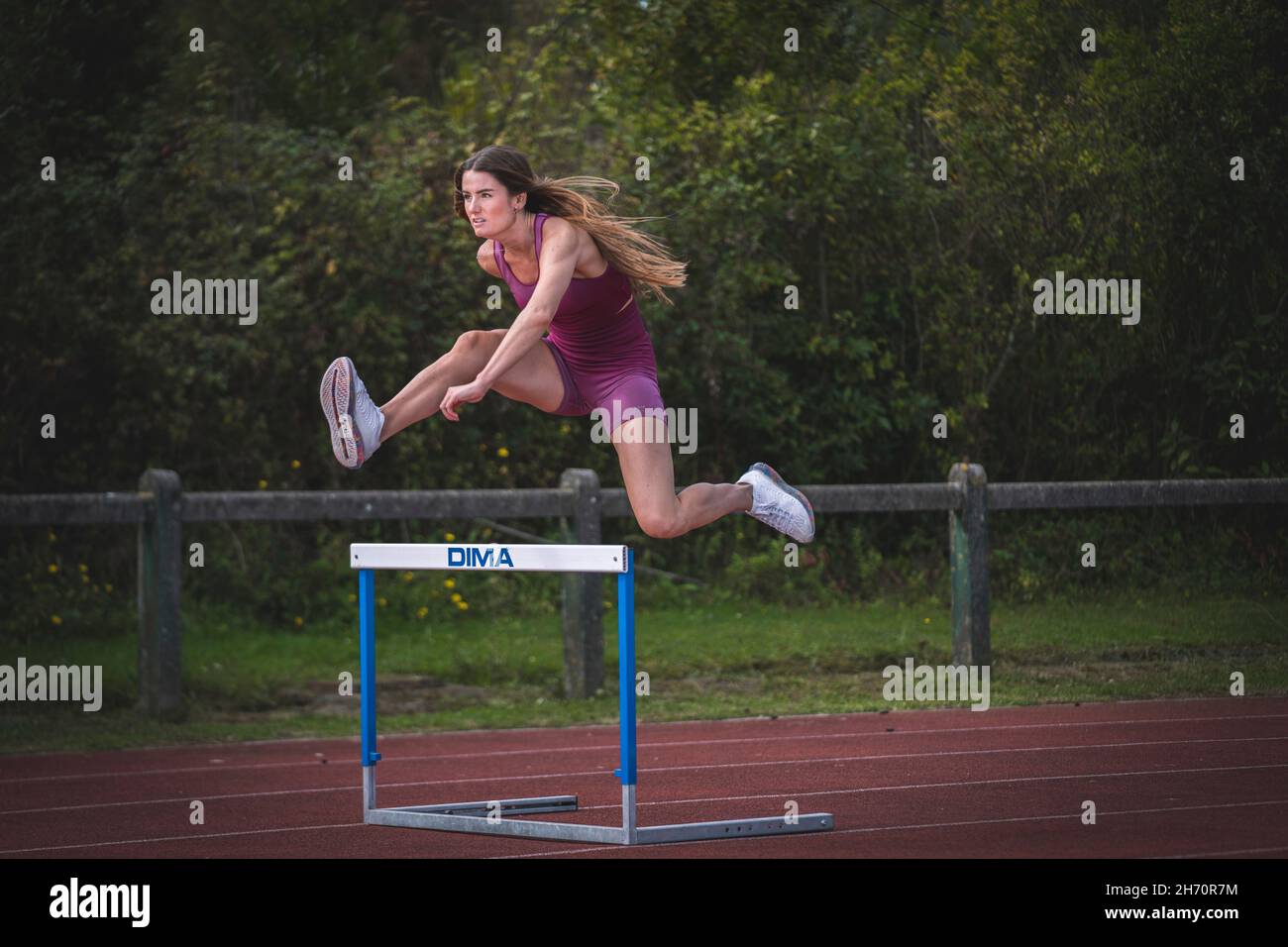Athlete model girl jumping hurdles on the running track Stock Photo Alamy