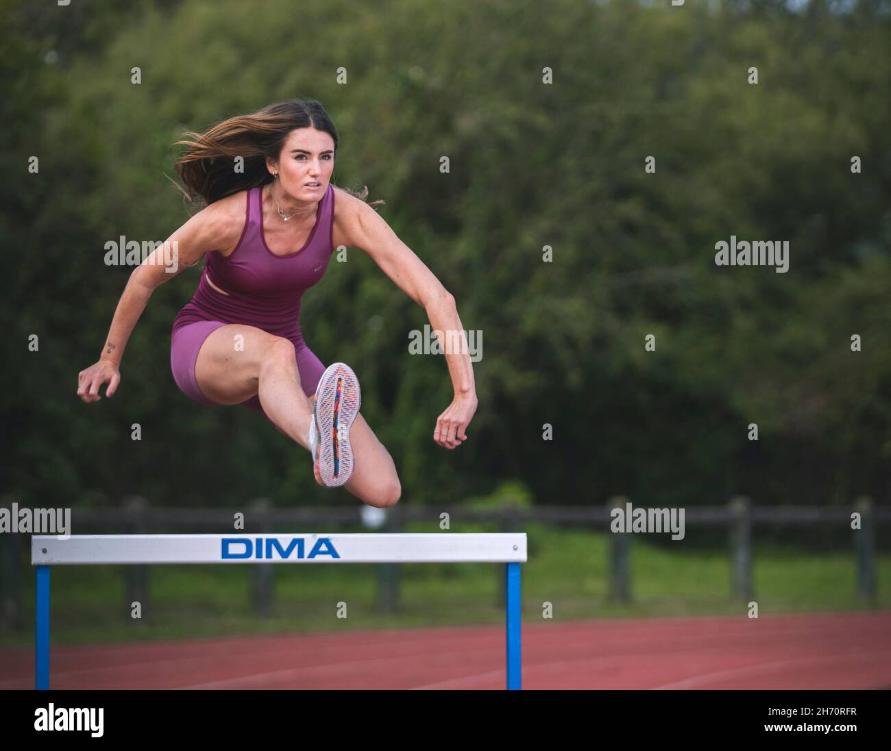 Athlete model girl jumping hurdles on the running track Stock Photo Alamy