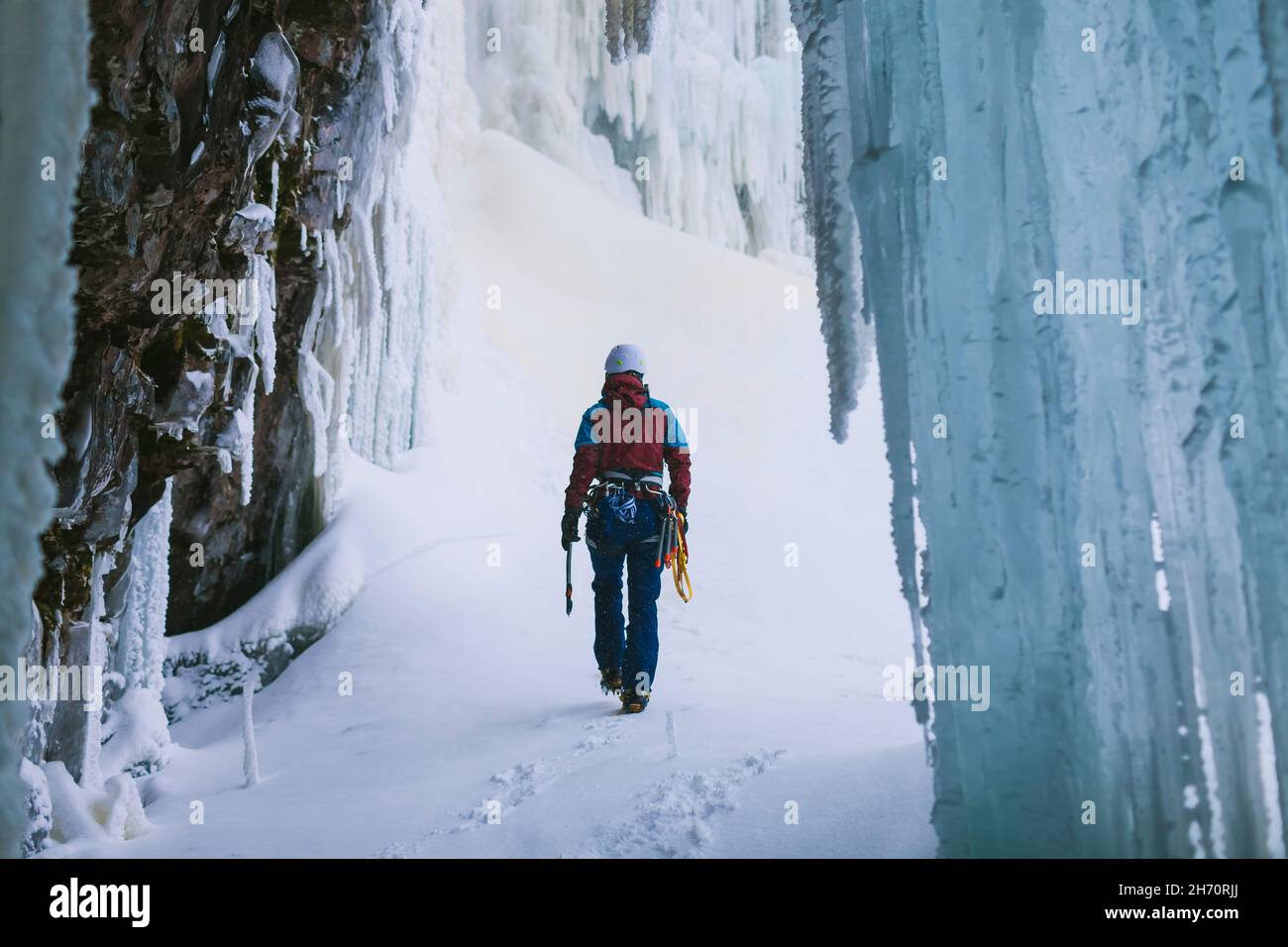 Female ice climber walking on snow Stock Photo