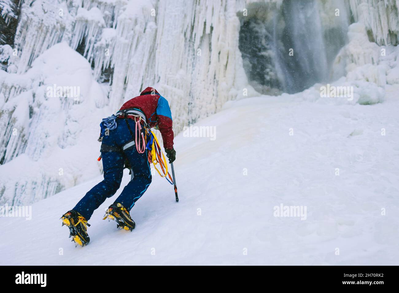 Female ice climber ascending snowy hill Stock Photo