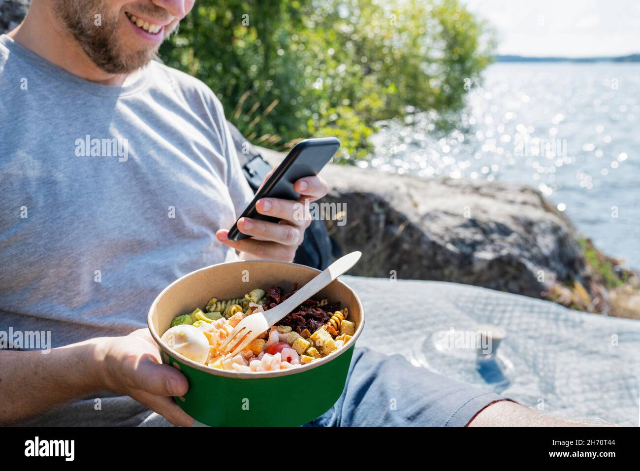 Man holding bowl with food and using phone Stock Photo