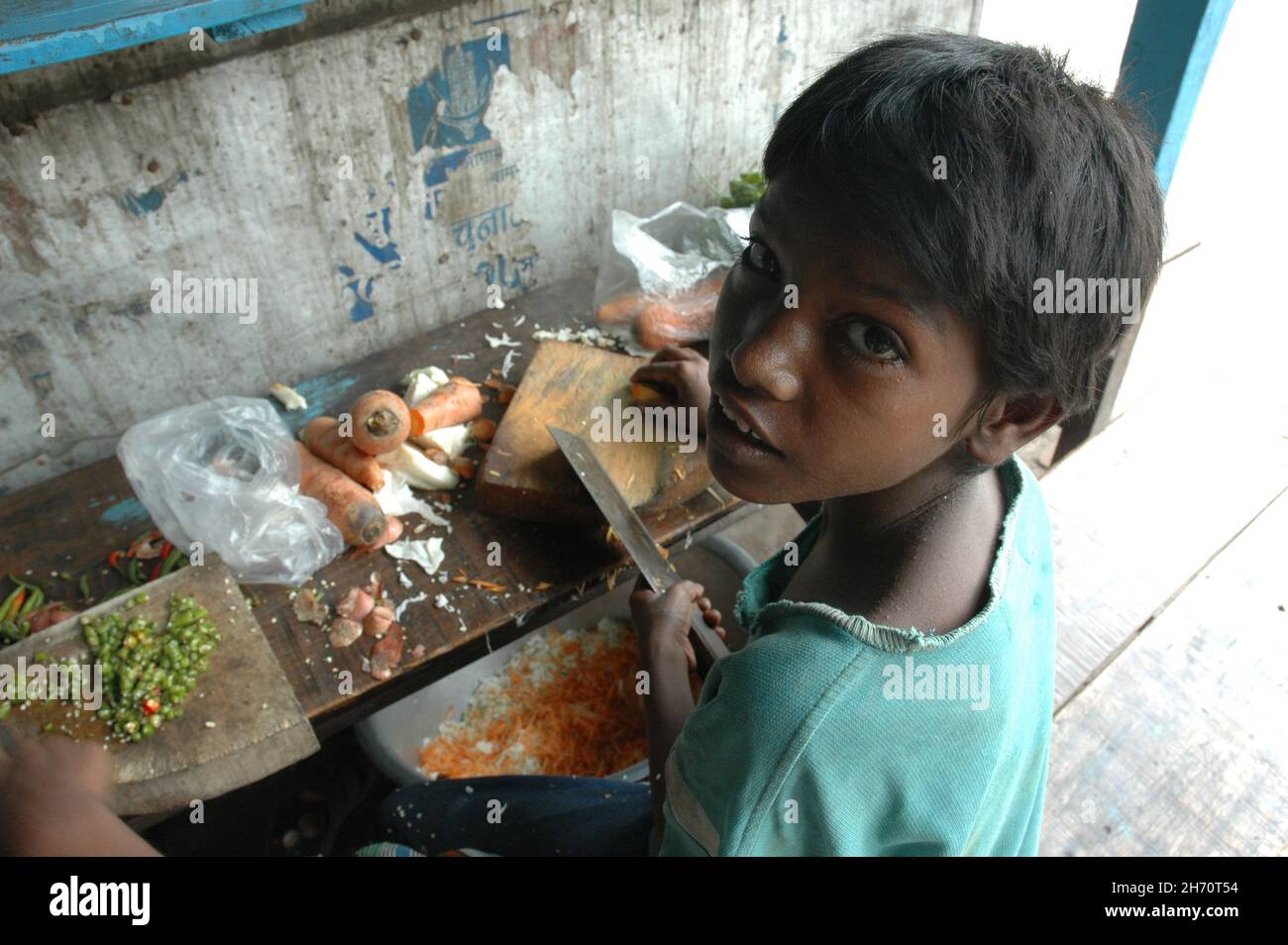 A young child cutting vegetables. India. Stock Photo