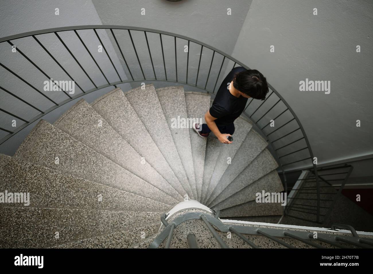 Young woman walking down spiral staircase Stock Photo