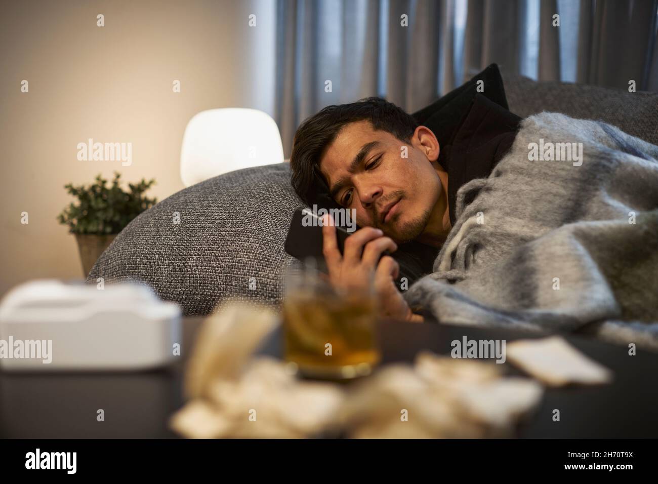 Young man lying on sofa and using smart phone Stock Photo