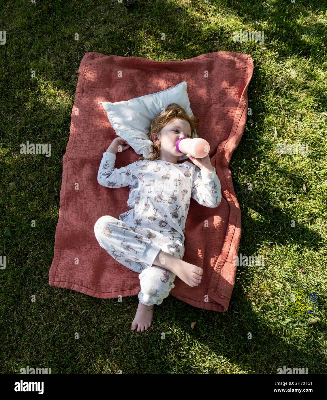Child lying on grass and drinking from bottle Stock Photo