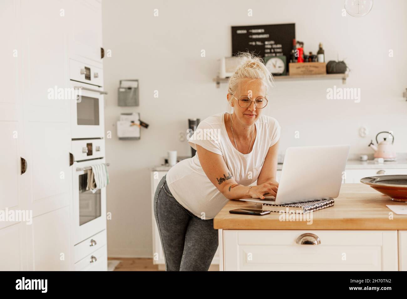Woman using laptop in kitchen Stock Photo