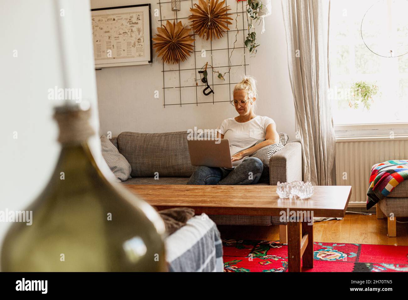 Smiling woman using laptop on sofa Stock Photo