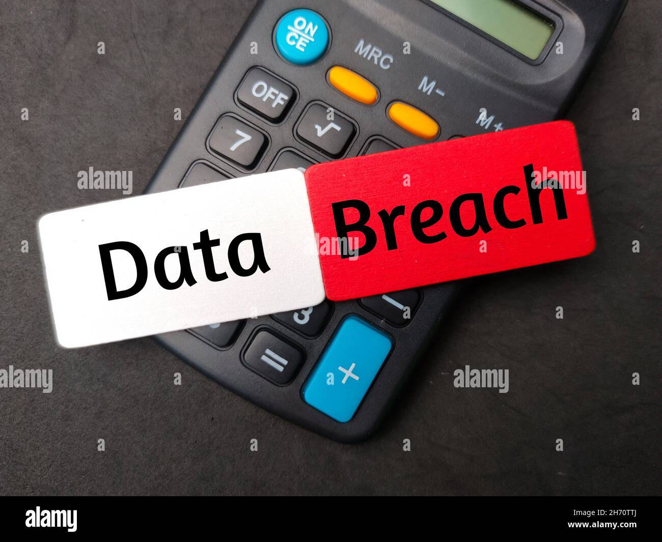 Colored wooden board written with text Data Breach with calculator on
