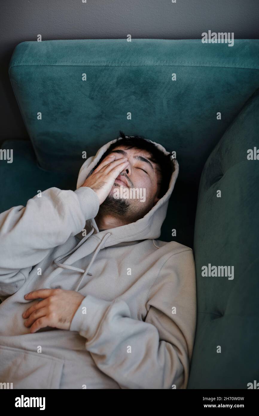 Ill man on sofa with hand covering face Stock Photo