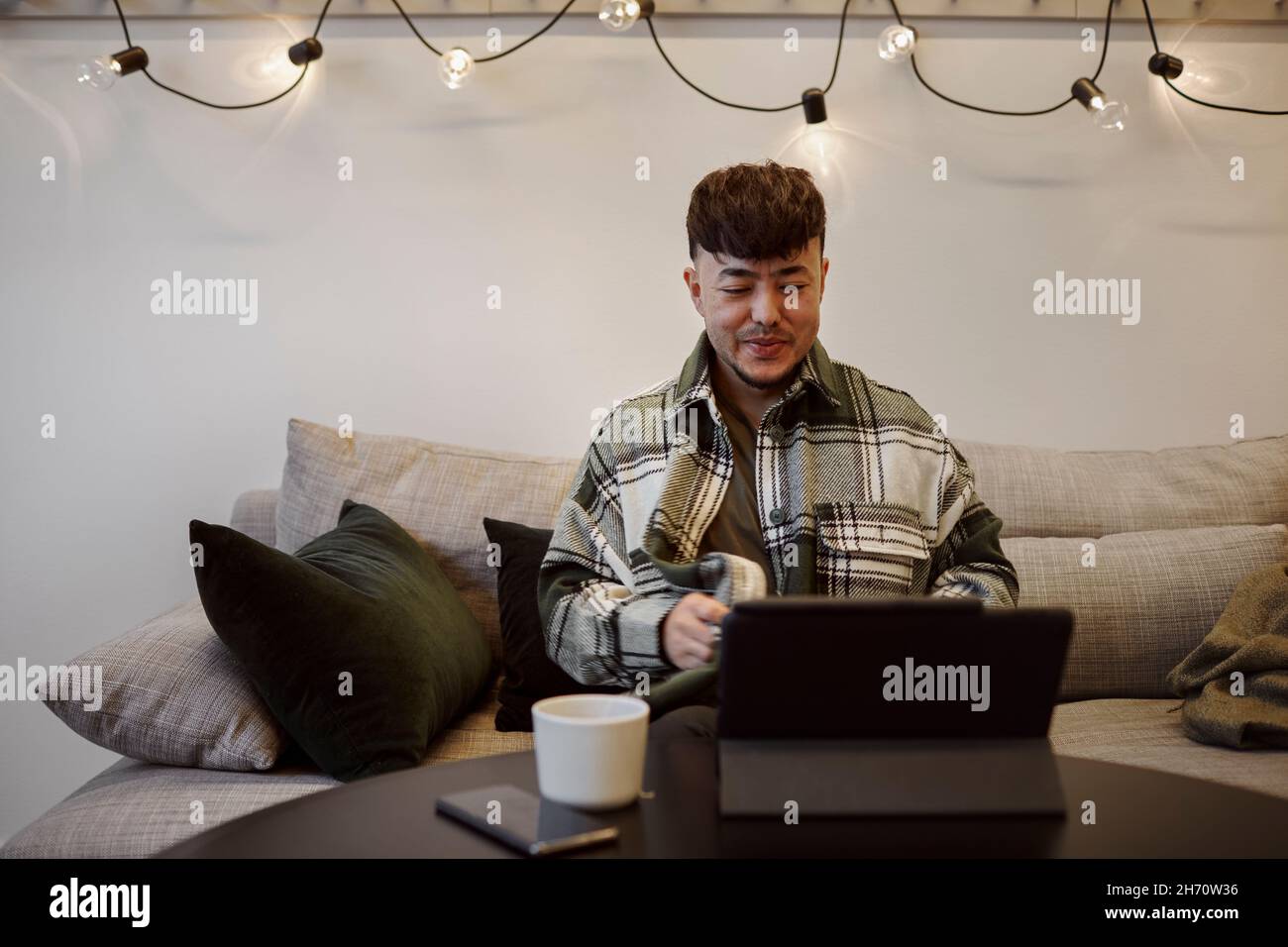 Man on sofa using digital tablet Stock Photo