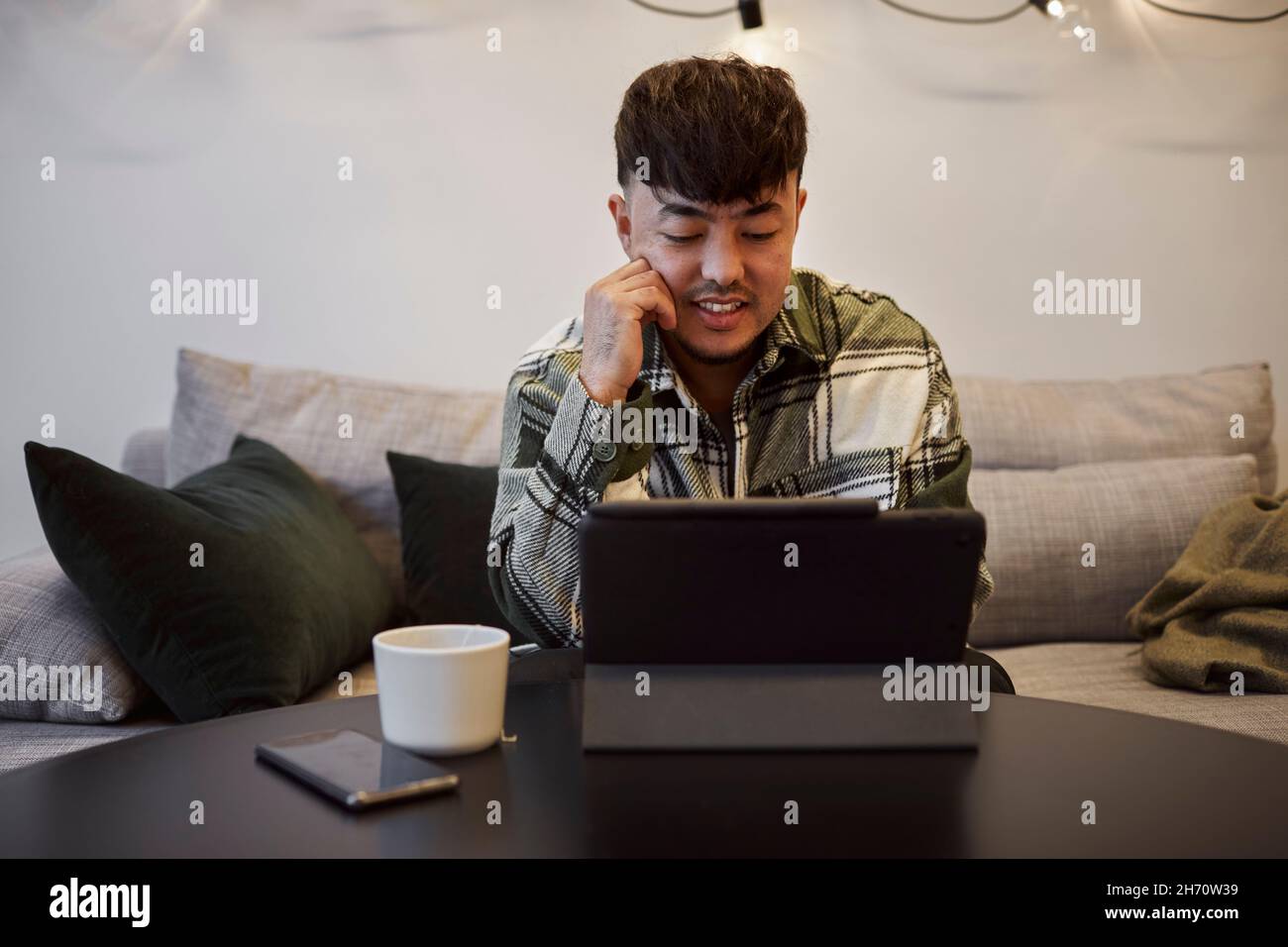 Man on sofa using digital tablet Stock Photo