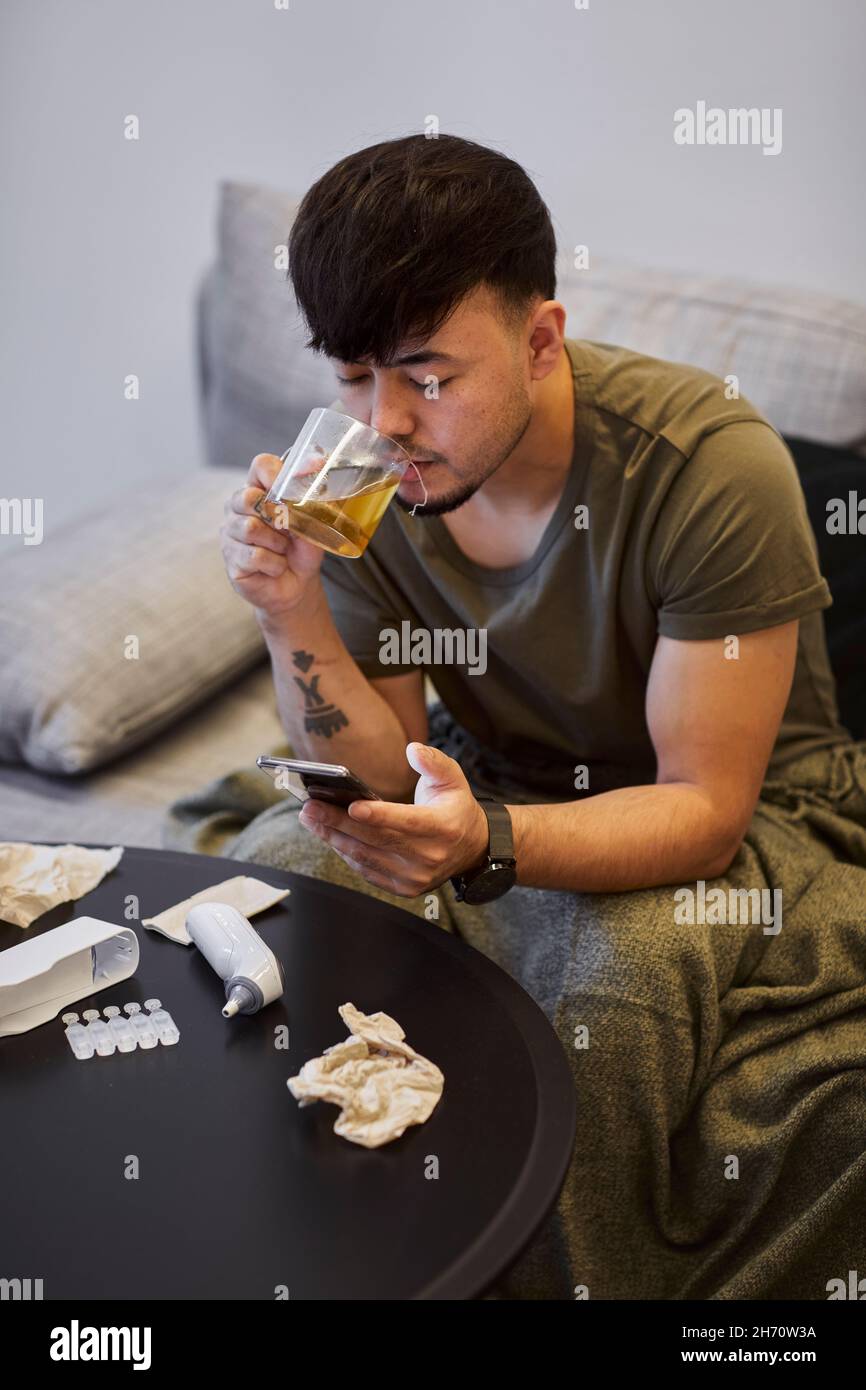 Man on sofa using cell phone Stock Photo