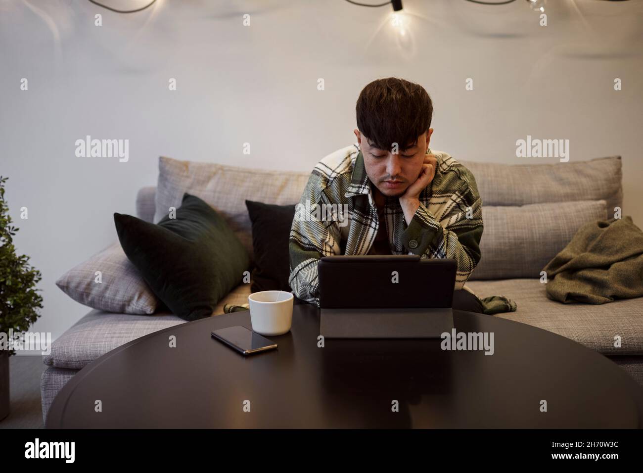 Man on sofa using digital tablet Stock Photo