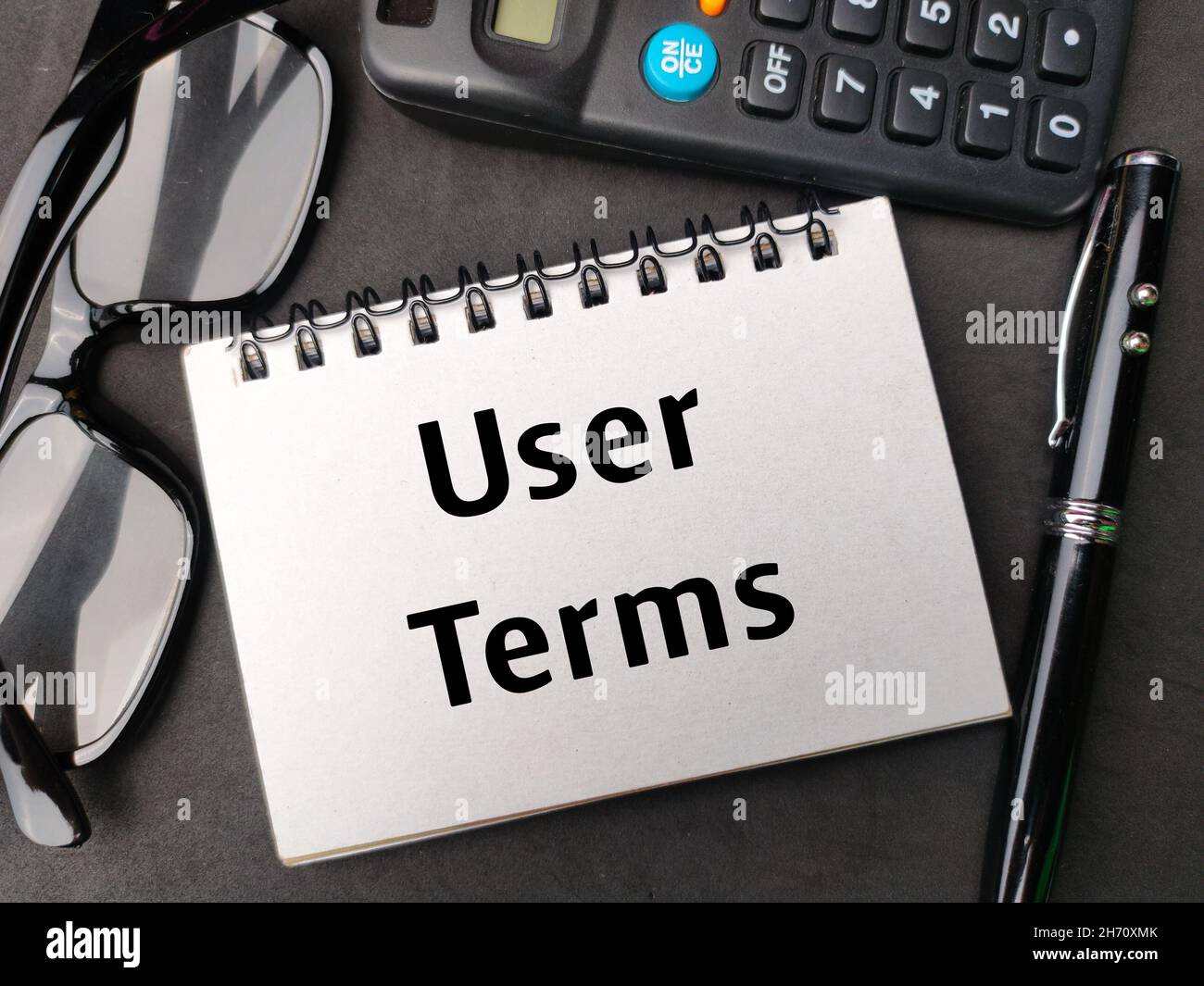 Notebook,glasses,calculator and pen written with text User Terms on black background. Stock Photo
