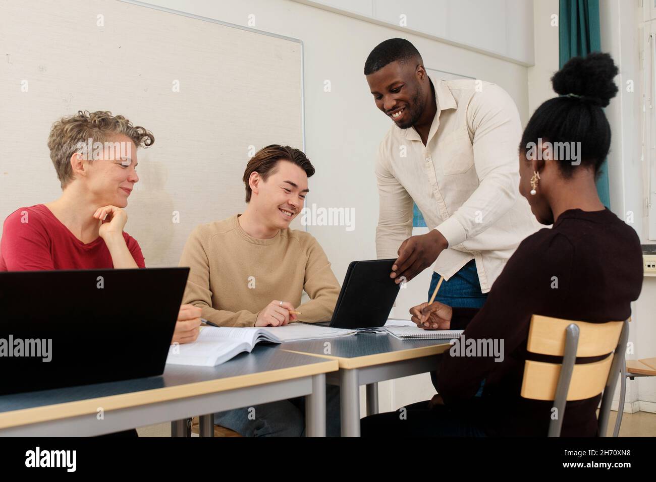 Teacher helping students in classroom Stock Photo